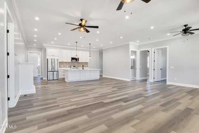 unfurnished living room featuring light wood-style floors, baseboards, crown molding, and recessed lighting