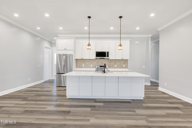 kitchen with a center island with sink, stainless steel appliances, light countertops, white cabinetry, and a sink