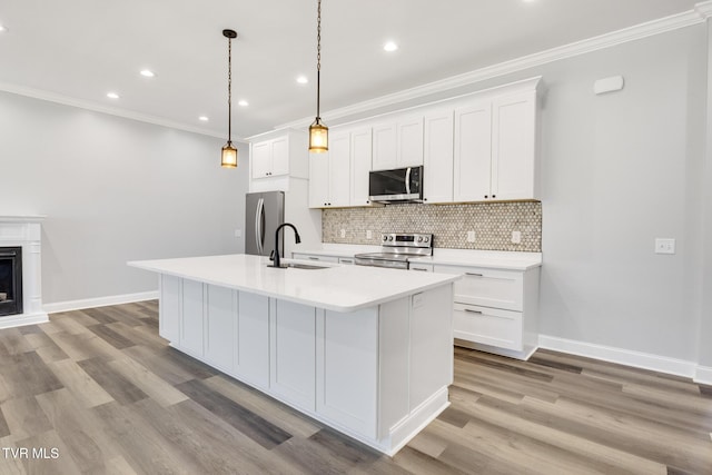 kitchen with tasteful backsplash, appliances with stainless steel finishes, white cabinetry, a sink, and an island with sink