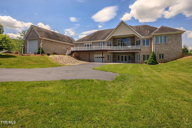 back of house with a deck, aphalt driveway, a lawn, and brick siding