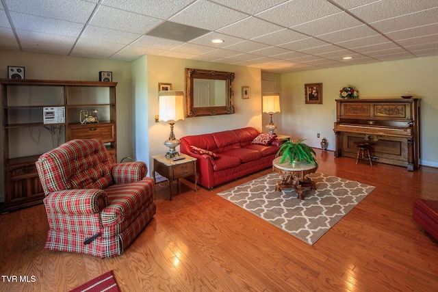 living area with a drop ceiling and wood finished floors