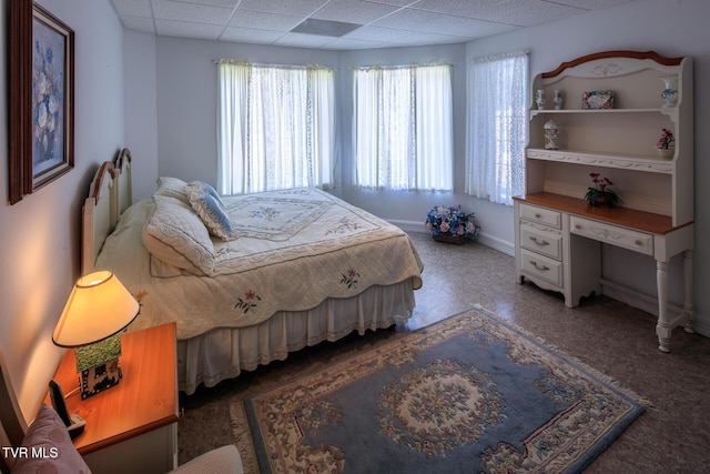 bedroom featuring baseboards and a drop ceiling