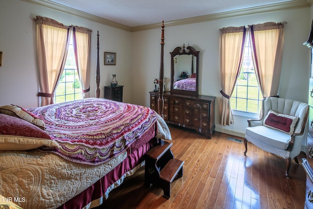 bedroom featuring visible vents, crown molding, baseboards, and wood finished floors