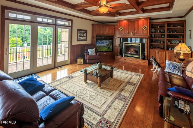 living area featuring crown molding, coffered ceiling, dark wood-type flooring, and wainscoting