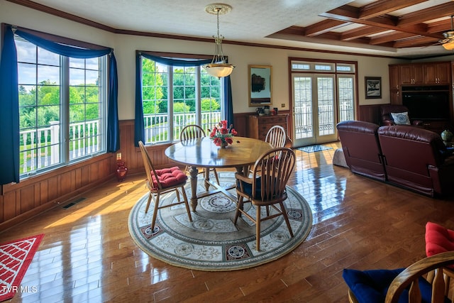 dining space featuring a textured ceiling, light wood-style flooring, a wainscoted wall, coffered ceiling, and visible vents