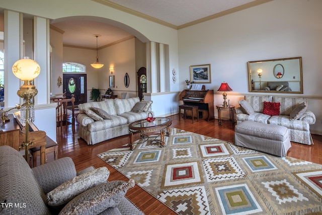 living area featuring crown molding, arched walkways, and dark wood-type flooring