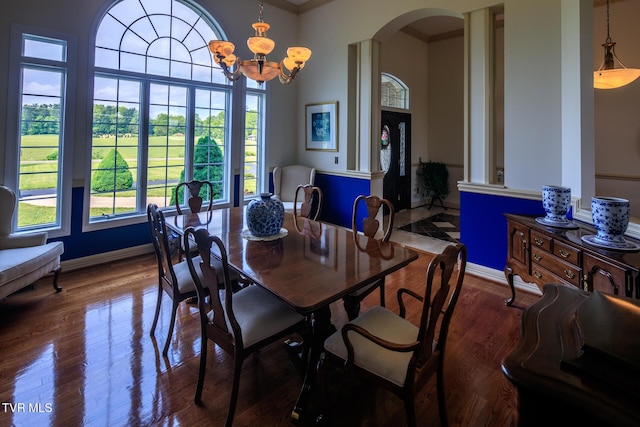 dining room with arched walkways, baseboards, and wood finished floors