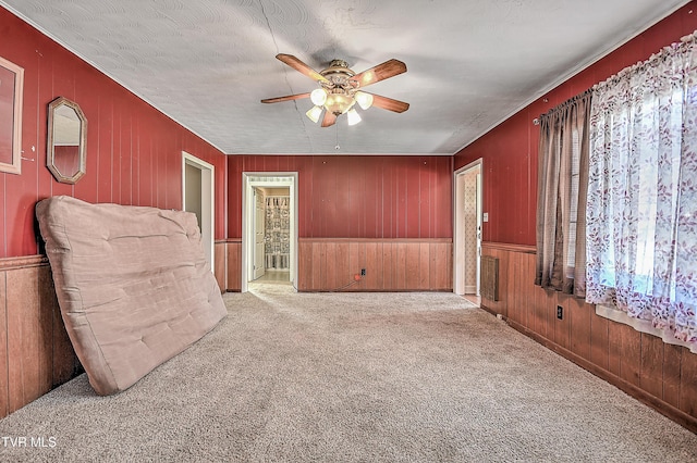 carpeted empty room featuring ceiling fan, a textured ceiling, and wooden walls