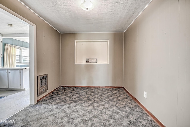 empty room with heating unit, crown molding, carpet flooring, and a textured ceiling