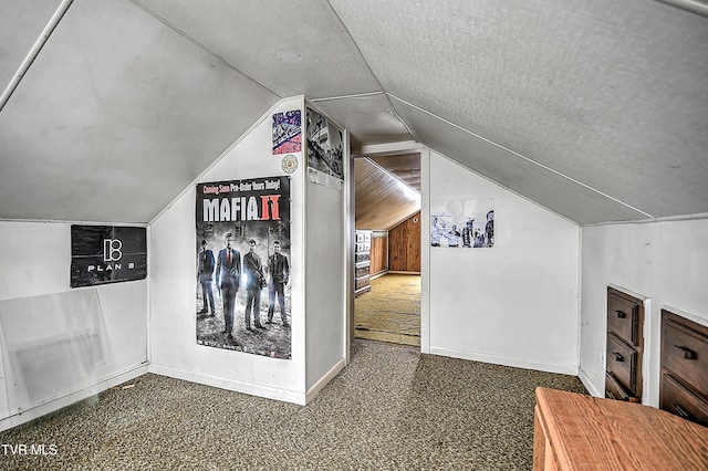 additional living space featuring lofted ceiling and dark colored carpet