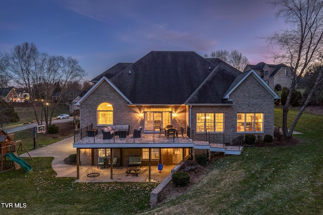 rear view of property with a playground, a yard, a patio, brick siding, and outdoor lounge area