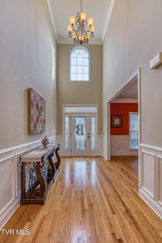 entryway featuring a chandelier, light wood-type flooring, a healthy amount of sunlight, and ornamental molding