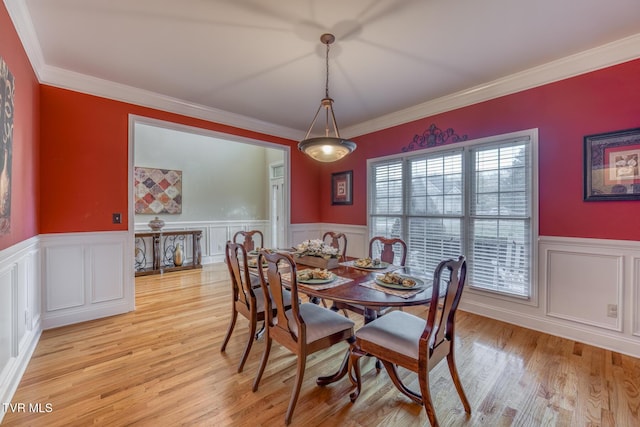 dining room featuring a wainscoted wall, crown molding, and light wood-style floors