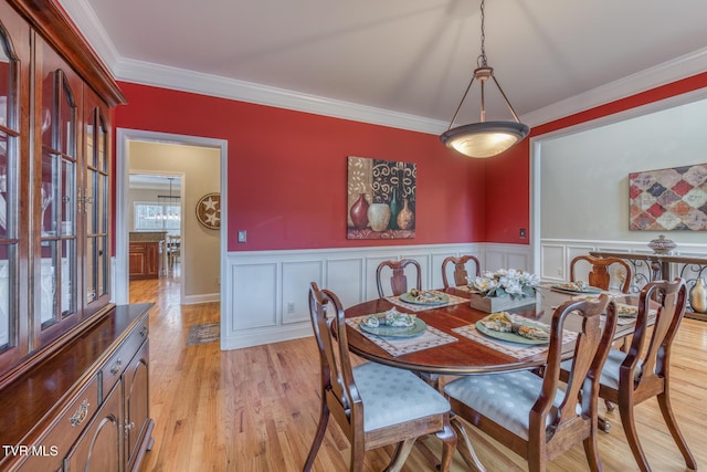 dining room with wainscoting, crown molding, and light wood-style flooring