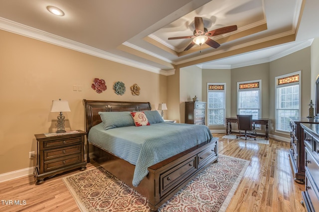 bedroom featuring light wood finished floors, a raised ceiling, and crown molding