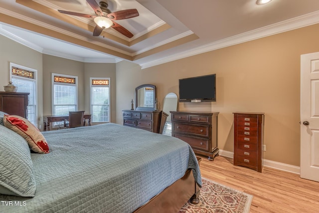 bedroom featuring baseboards, light wood-style flooring, ceiling fan, ornamental molding, and a tray ceiling