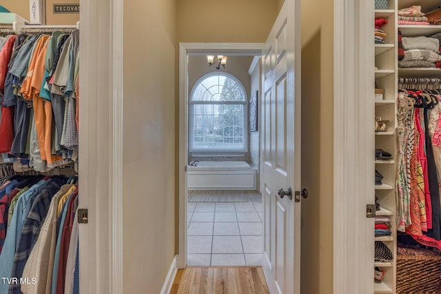 spacious closet featuring a notable chandelier and light tile patterned floors