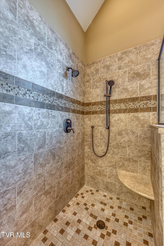 full bathroom featuring tiled shower and vaulted ceiling