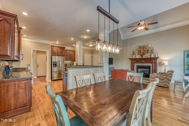 dining room with a ceiling fan, ornamental molding, light wood-type flooring, a fireplace, and recessed lighting