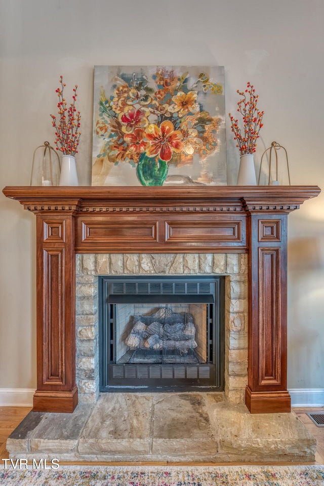 room details with a fireplace with raised hearth, visible vents, and baseboards