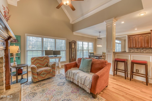 living room with light wood-type flooring, decorative columns, ornamental molding, and ceiling fan