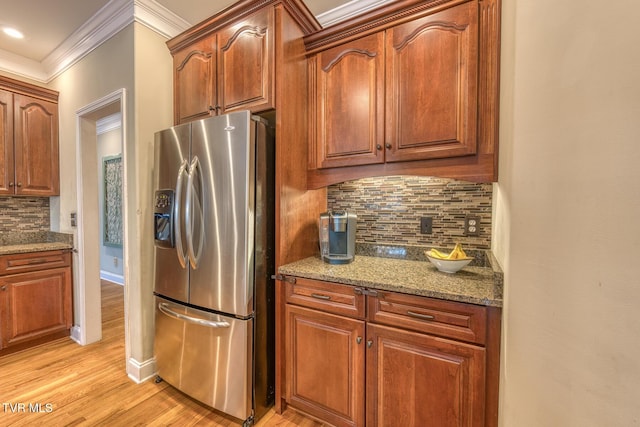 kitchen featuring light stone counters, light wood-style flooring, stainless steel refrigerator with ice dispenser, backsplash, and crown molding