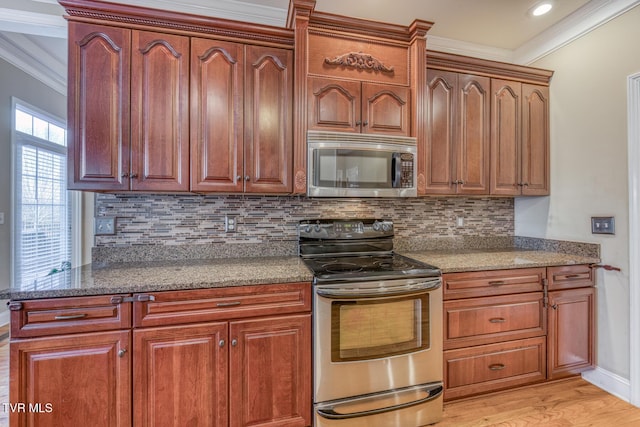 kitchen featuring tasteful backsplash, light wood-style flooring, appliances with stainless steel finishes, dark stone countertops, and crown molding