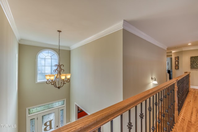 corridor featuring crown molding, wood finished floors, an upstairs landing, and an inviting chandelier