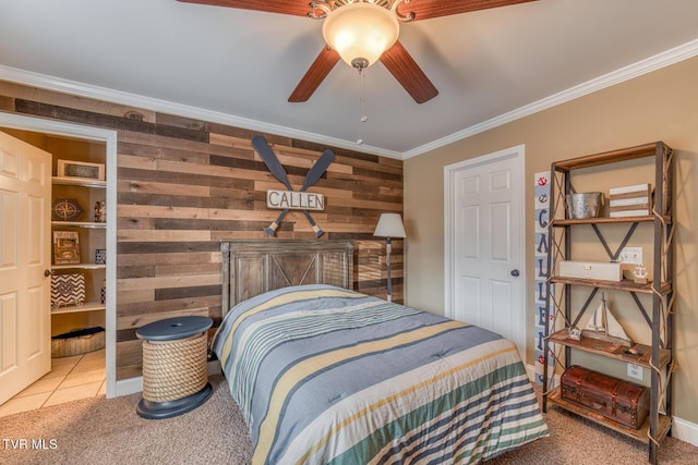 bedroom with ceiling fan, light tile patterned flooring, light carpet, wood walls, and crown molding