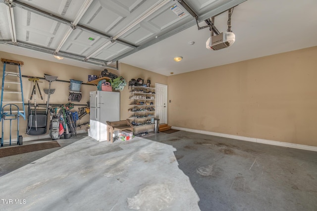 garage with a garage door opener, freestanding refrigerator, and baseboards