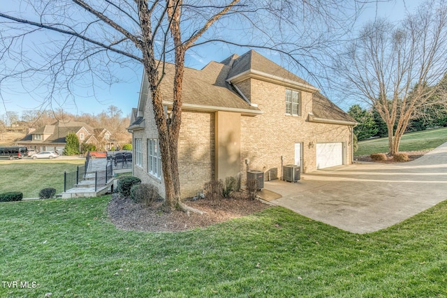 view of home's exterior with a yard, brick siding, central AC, and driveway