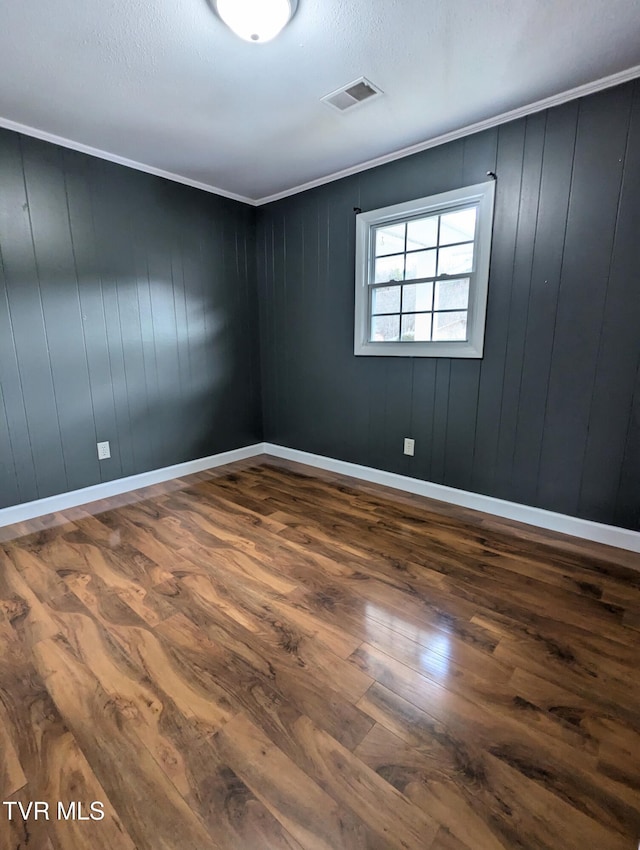 empty room featuring crown molding and wood-type flooring