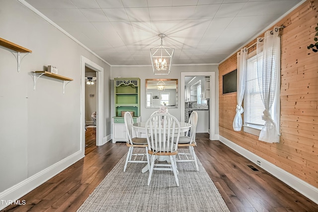 unfurnished dining area with an inviting chandelier, ornamental molding, dark hardwood / wood-style floors, and wood walls