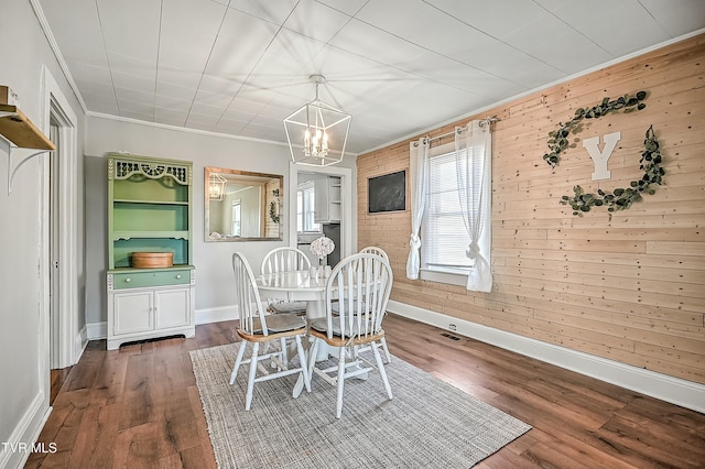 dining area featuring an inviting chandelier, ornamental molding, dark hardwood / wood-style floors, and wood walls