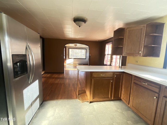 kitchen with light floors, a peninsula, light countertops, stainless steel fridge with ice dispenser, and open shelves