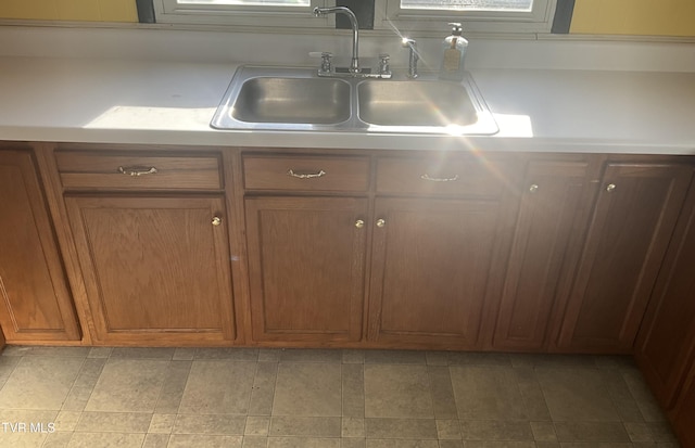 kitchen featuring light countertops, brown cabinetry, and a sink