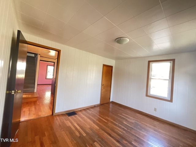 empty room with baseboards, visible vents, and hardwood / wood-style floors