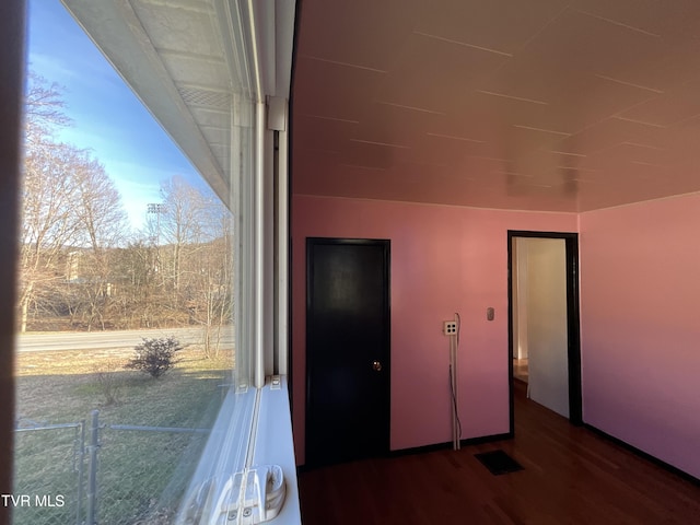 unfurnished bedroom featuring multiple windows, wood finished floors, and visible vents