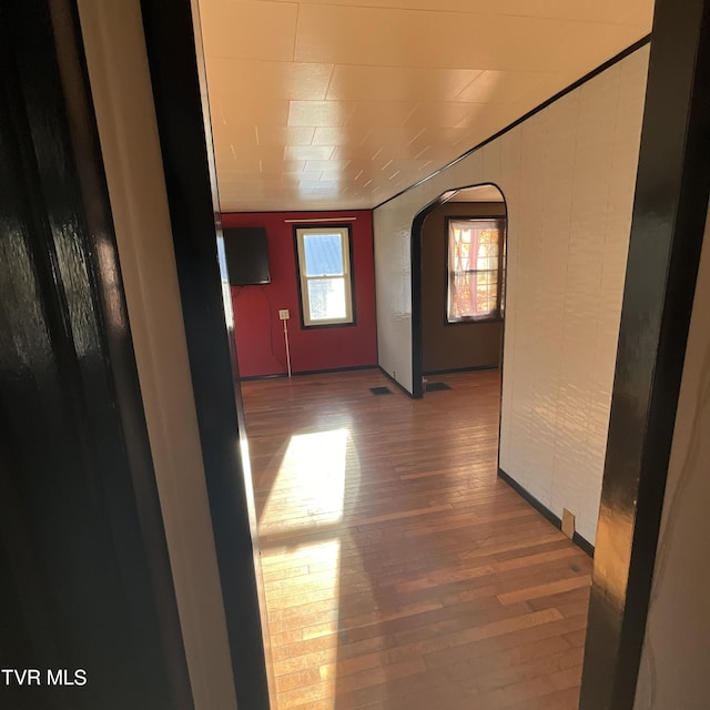 hallway with arched walkways and wood finished floors