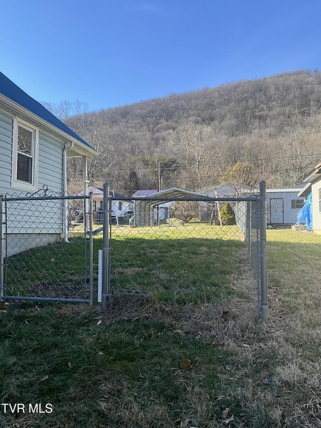 view of yard with a gate, fence, and a wooded view