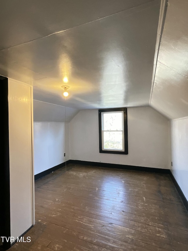 additional living space featuring hardwood / wood-style flooring, vaulted ceiling, and baseboards