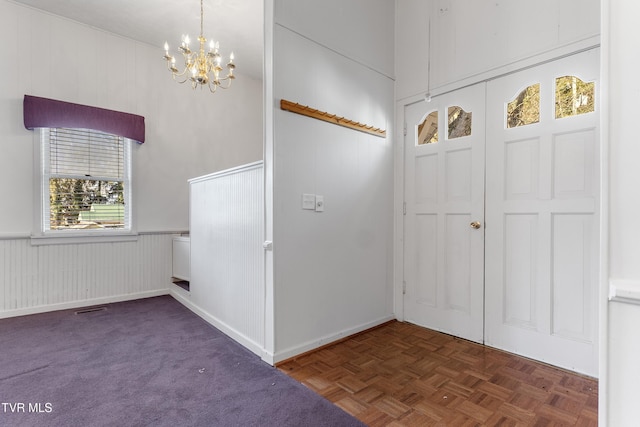 foyer entrance with a notable chandelier and dark parquet flooring