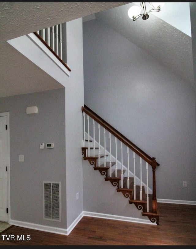 stairs with hardwood / wood-style flooring and vaulted ceiling