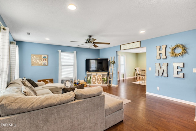 living room featuring ceiling fan, a wealth of natural light, a textured ceiling, and dark hardwood / wood-style floors