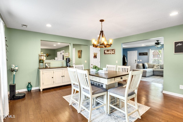 dining area featuring dark hardwood / wood-style floors and ceiling fan with notable chandelier