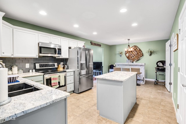 kitchen featuring appliances with stainless steel finishes, white cabinetry, a kitchen island, and decorative light fixtures
