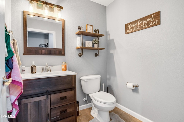 bathroom with toilet, vanity, and tile patterned flooring