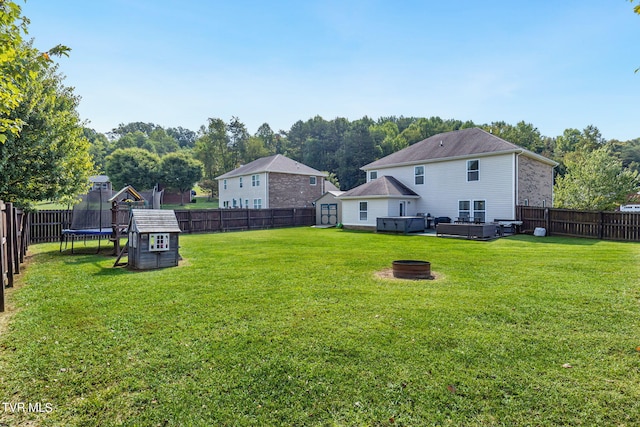 view of yard with a hot tub, a playground, a trampoline, and an outdoor fire pit
