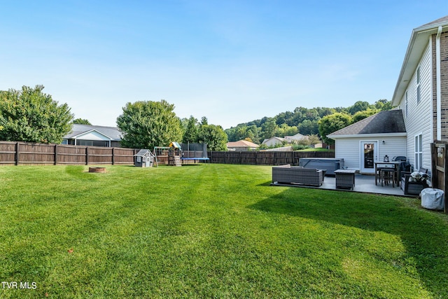 view of yard with a trampoline, a patio area, and a hot tub