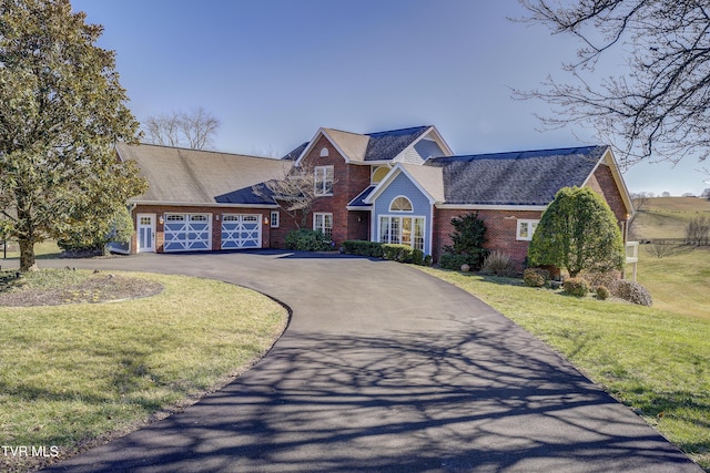 view of front facade with driveway, a front lawn, and brick siding